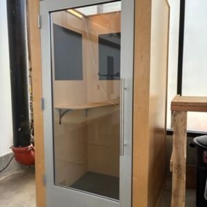 A used Zenbooth Solo office phone booth featuring a natural wood exterior, full-profile glass door, skylight ceiling, and an integrated desk, providing a soundproof privacy pod for open offices.