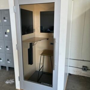 A used Zenbooth Solo office phone booth with a white exterior finish, full-profile glass door, skylight ceiling, and an integrated electric height-adjustable desk, providing a soundproof privacy pod for open offices.