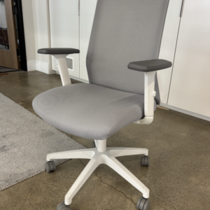 A used Poppin Nomad ergonomic task chair featuring a breathable mesh back, an upholstered seat cushion, height-adjustable arms, and a molded nylon base with casters.