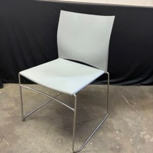 A used Source International Tier stack chair featuring a sleek, modern design with a durable seat and backrest, supported by a sturdy wire sled base designed for high-density stacking.
